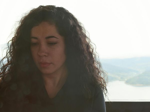 Person meditating peacefully with soft lighting in the background.